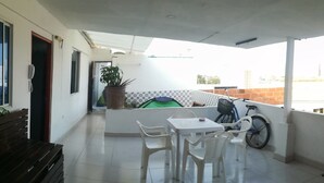 A balcony with a table and chairs, a refrigerator, and a view of the cityscape. - Sunset Terrace - Hostel (Cartagena)