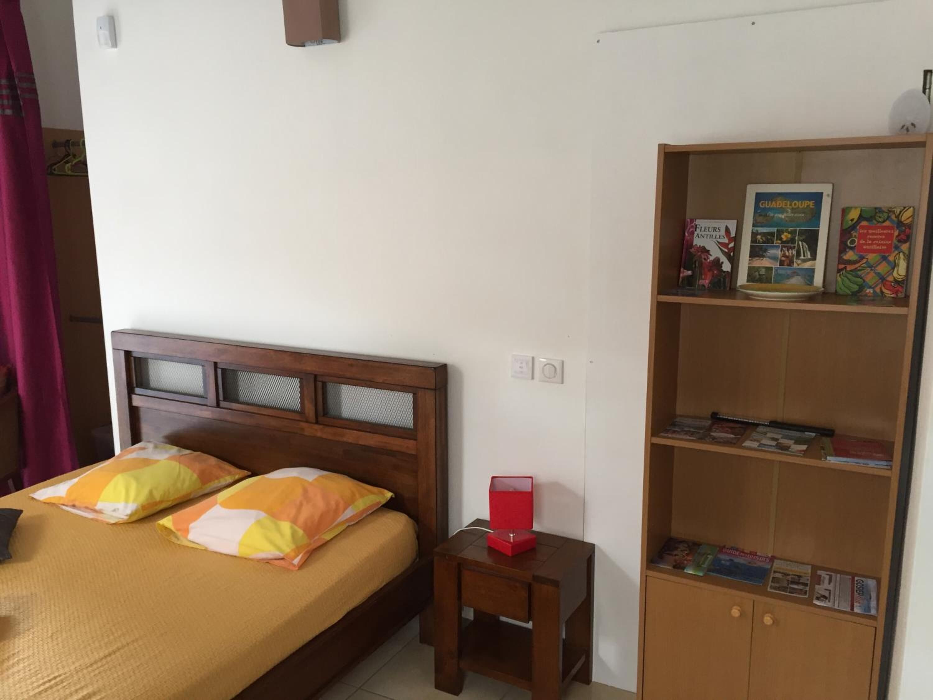 A bedroom with a bed, a nightstand, and a bookshelf.