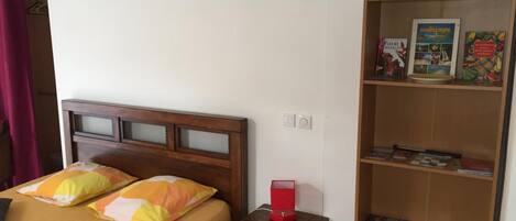Un dormitorio con cama, mesita de noche y estantería.