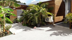 A modern house with a wooden exterior, surrounded by lush tropical plants and a gravel driveway. - Le Saint Georges (Le Gosier)