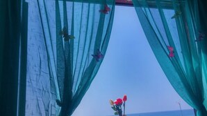 Una ventana con cortinas de encaje y un jarrón de flores.