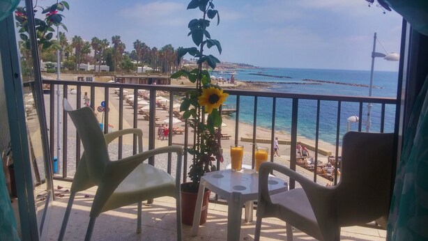 Un balcón con sillas y una mesa, con vistas a una playa y el mar.