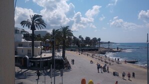 Un paseo marítimo frente a la playa con palmeras, una pasarela y vistas al mar.