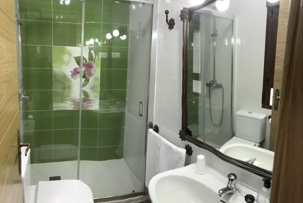 Une salle de bain avec une douche à parois de verre, un lavabo blanc et un grand miroir.