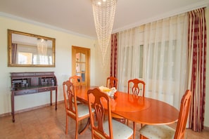 Un coin repas avec une table et des chaises en bois, un lustre et un grand miroir au mur.