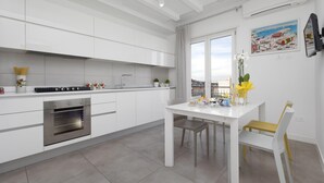 Eine moderne Küche mit weißen Schränken, einem eingebauten Backofen und einem Essbereich mit Tisch und Stühlen.