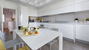 Eine moderne Küche mit weißen Schränken, einem Esstisch mit Stühlen und einem reichhaltigen Frühstücksbuffet.