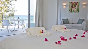 A hotel room with a bed, a sofa, a table with chairs, and a view of the sea. - Hotel Tofo Mar (Tofo)