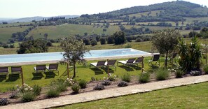A poolside area with lounge chairs and a view of rolling hills. - Marrucheti 82 (Campagnatico)