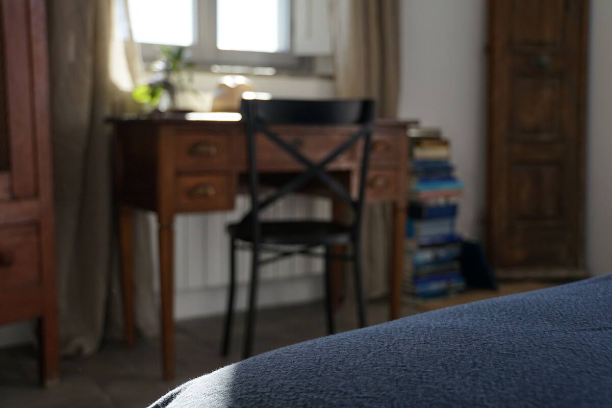 A room with a bed, a wooden desk, a chair, and a wardrobe.