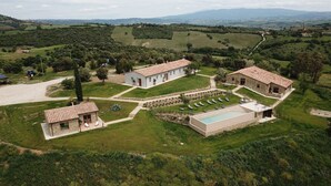 A rural property with a swimming pool, multiple buildings, and a tractor in the field. - Marrucheti 82 (Campagnatico)