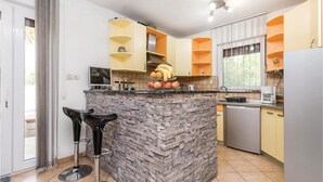 A modern kitchen with a central island, built-in appliances, and a dining area with a bar stool.