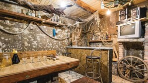 A rustic bar area with wooden furniture, a stone wall, and a vintage television.