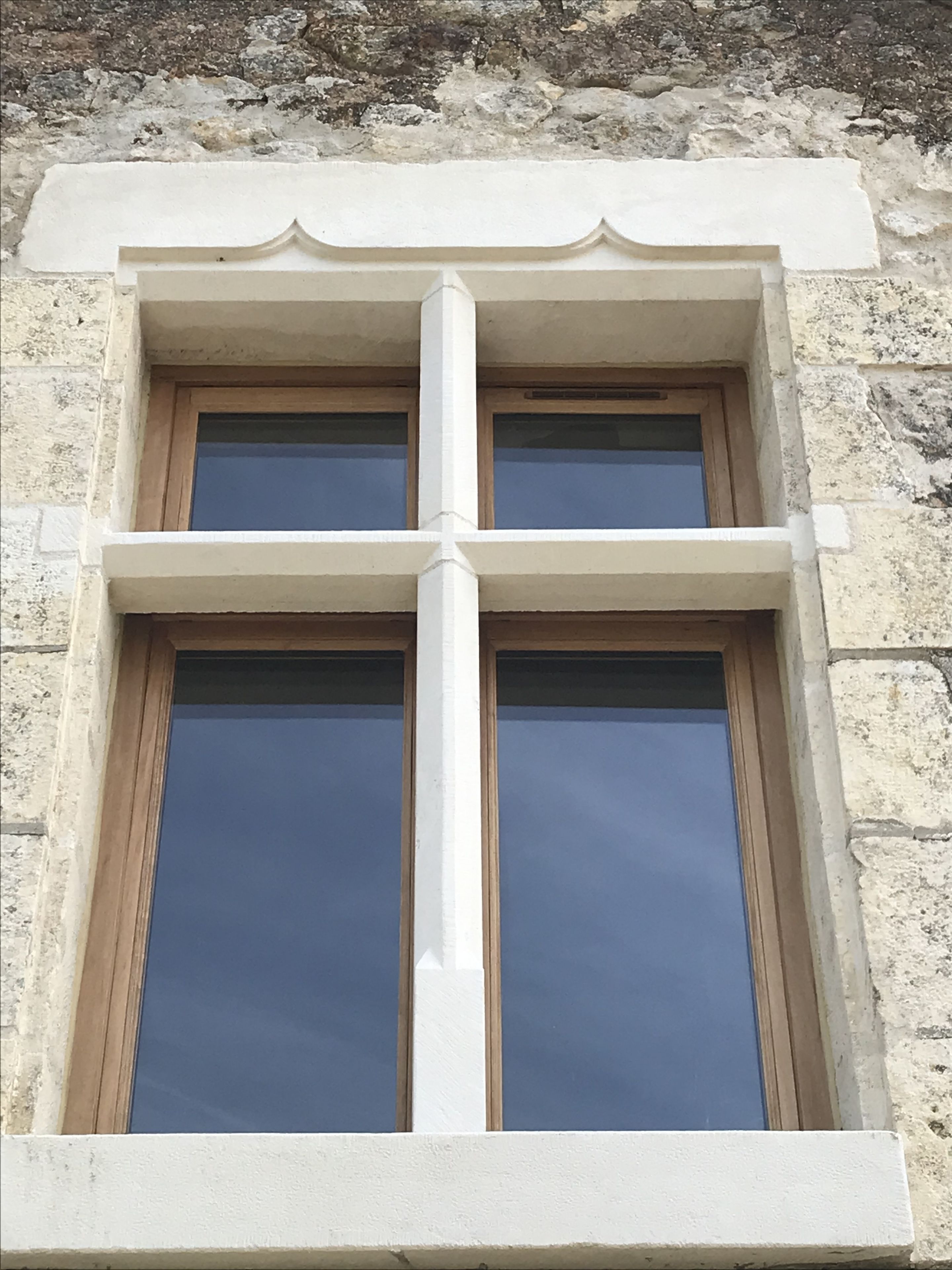 A window with a white frame and a decorative cross design at the top.