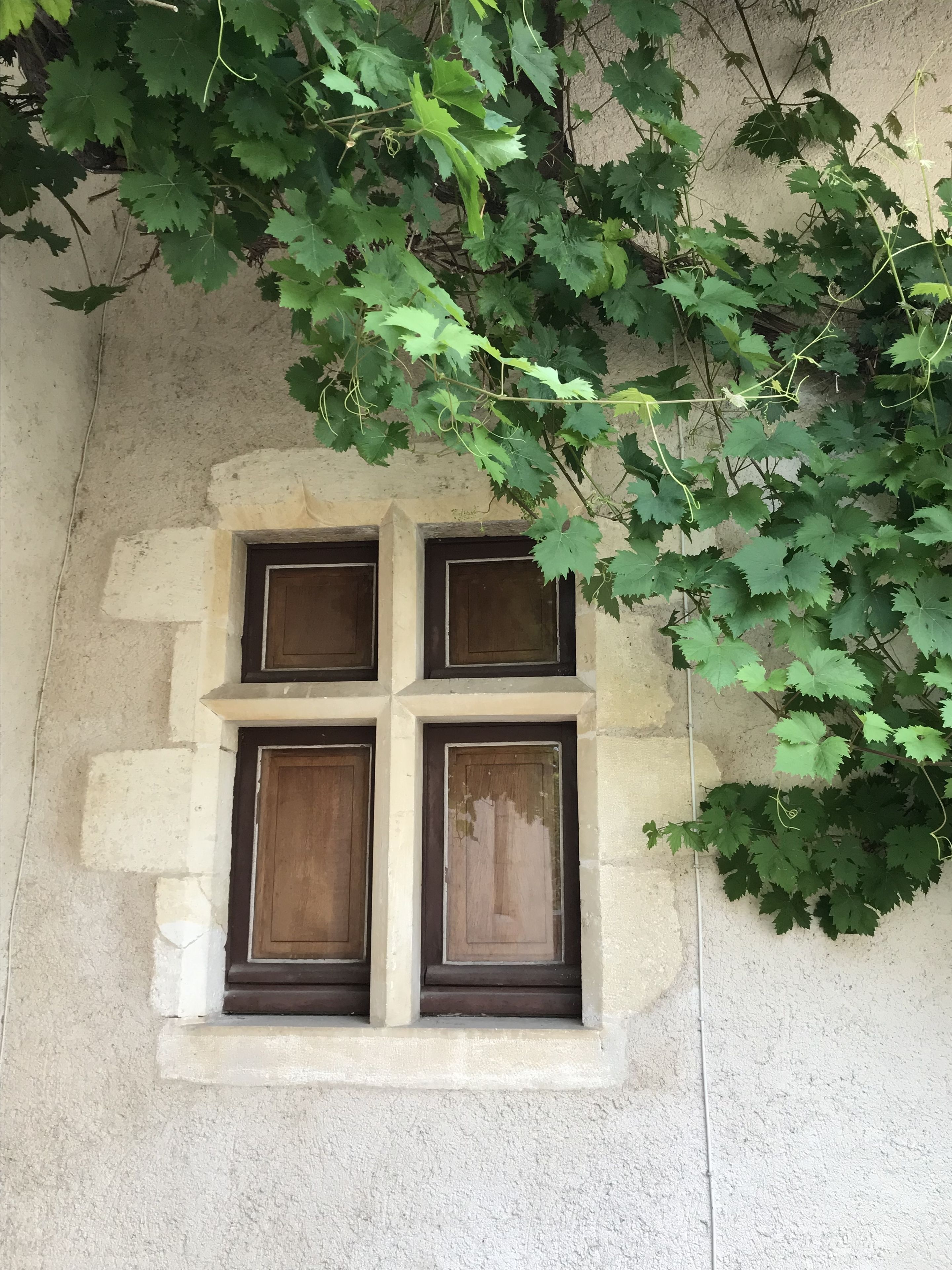Una pared de piedra con un ventanal que presenta cuatro paneles de madera.