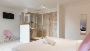 Een moderne hotelkamer met een groot bed, een douche en een flatscreen televisie aan de muur.