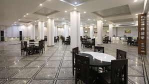 A spacious indoor area with multiple tables and chairs, a polished floor, and a high ceiling with recessed lighting. - Hotel Marc Royal (Agra)