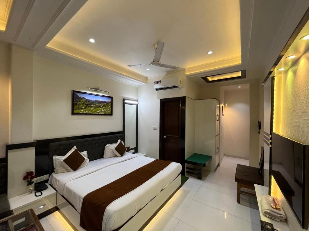 Una habitación de hotel con cama, mesita de noche y televisión instalada en la pared.