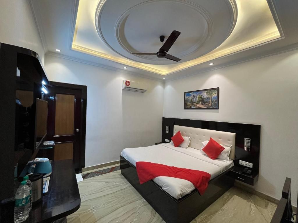 Habitación de hotel moderna con cama, ventilador de techo, un cuadro en la pared y una botella de agua sobre la mesita de noche.