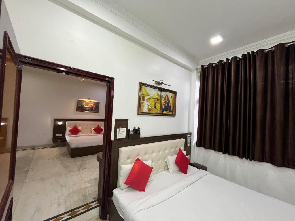 A hotel room with a bed, a mirror, a painting, and a window with curtains.