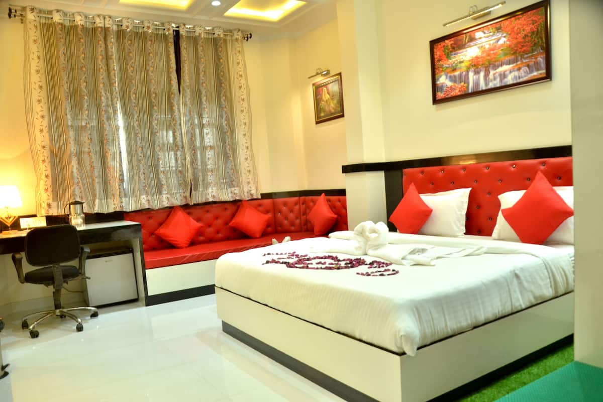 A hotel room with a bed, a desk, a chair, and a window with curtains.
