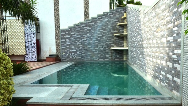 A swimming pool with a tiled wall and steps leading into it. - Hotel Marc Royal (Agra)