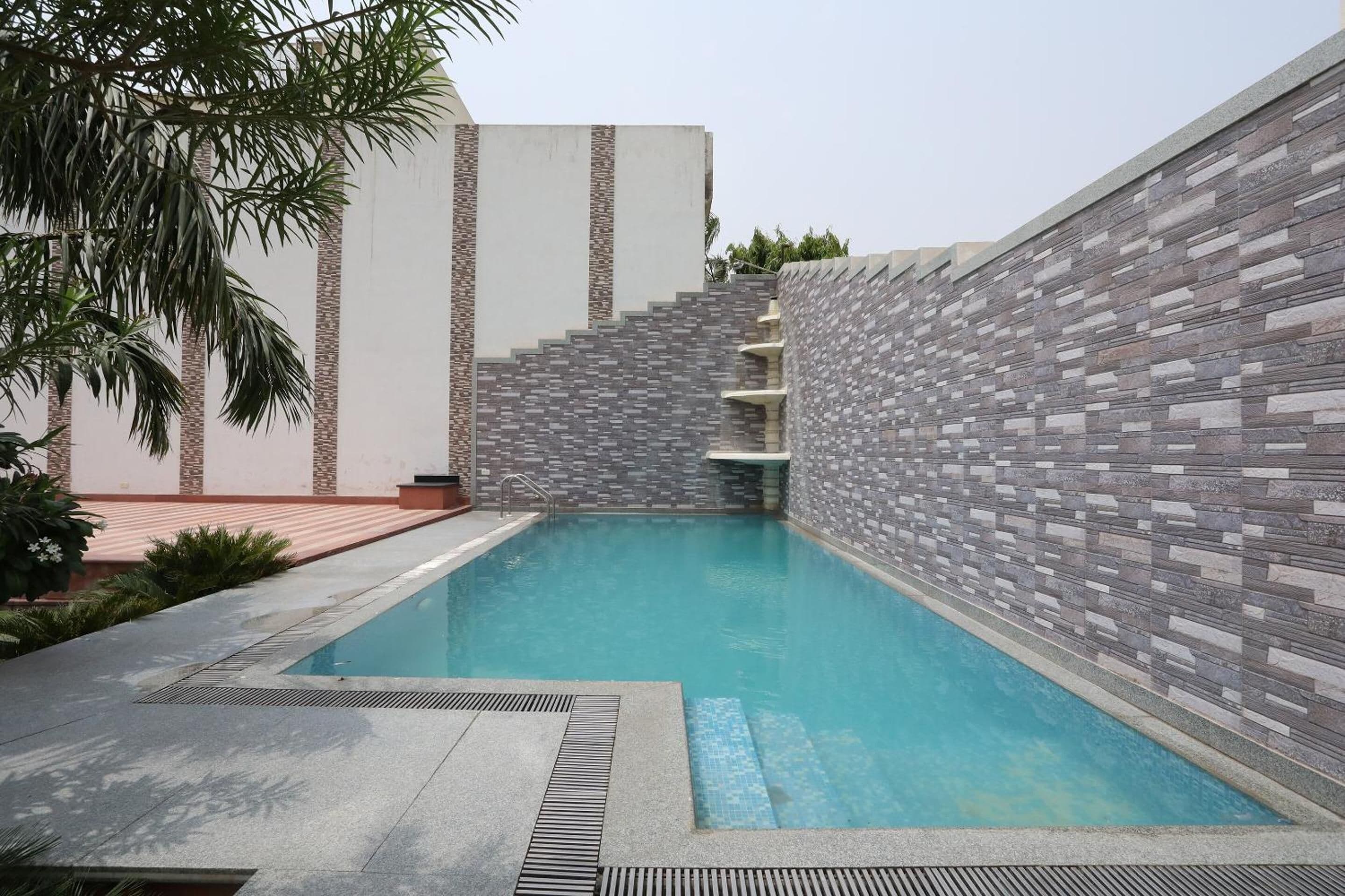 Una piscina con un muro de piedra y una palmera.