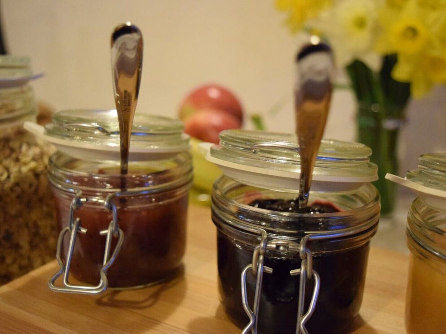 Several glass jars with metal clasps containing dark liquids, possibly jams or preserves, on a wooden surface.