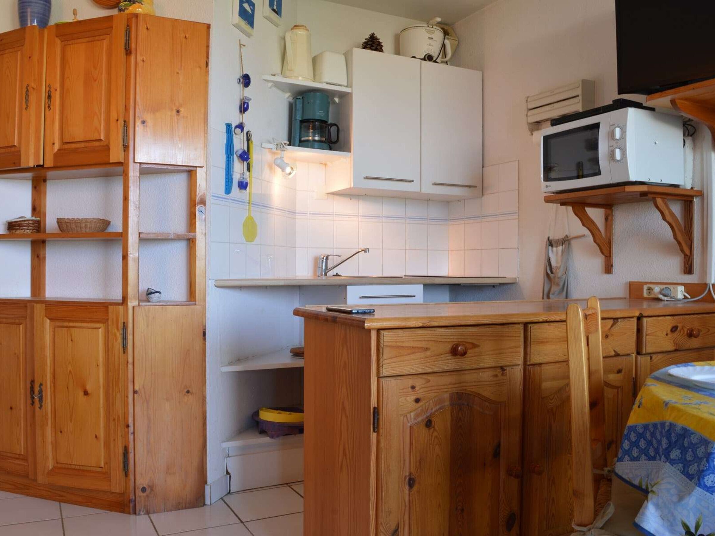 A compact kitchen with wooden cabinets, a microwave, and a sink.