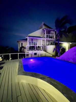 Une grande maison avec une piscine, de nuit.