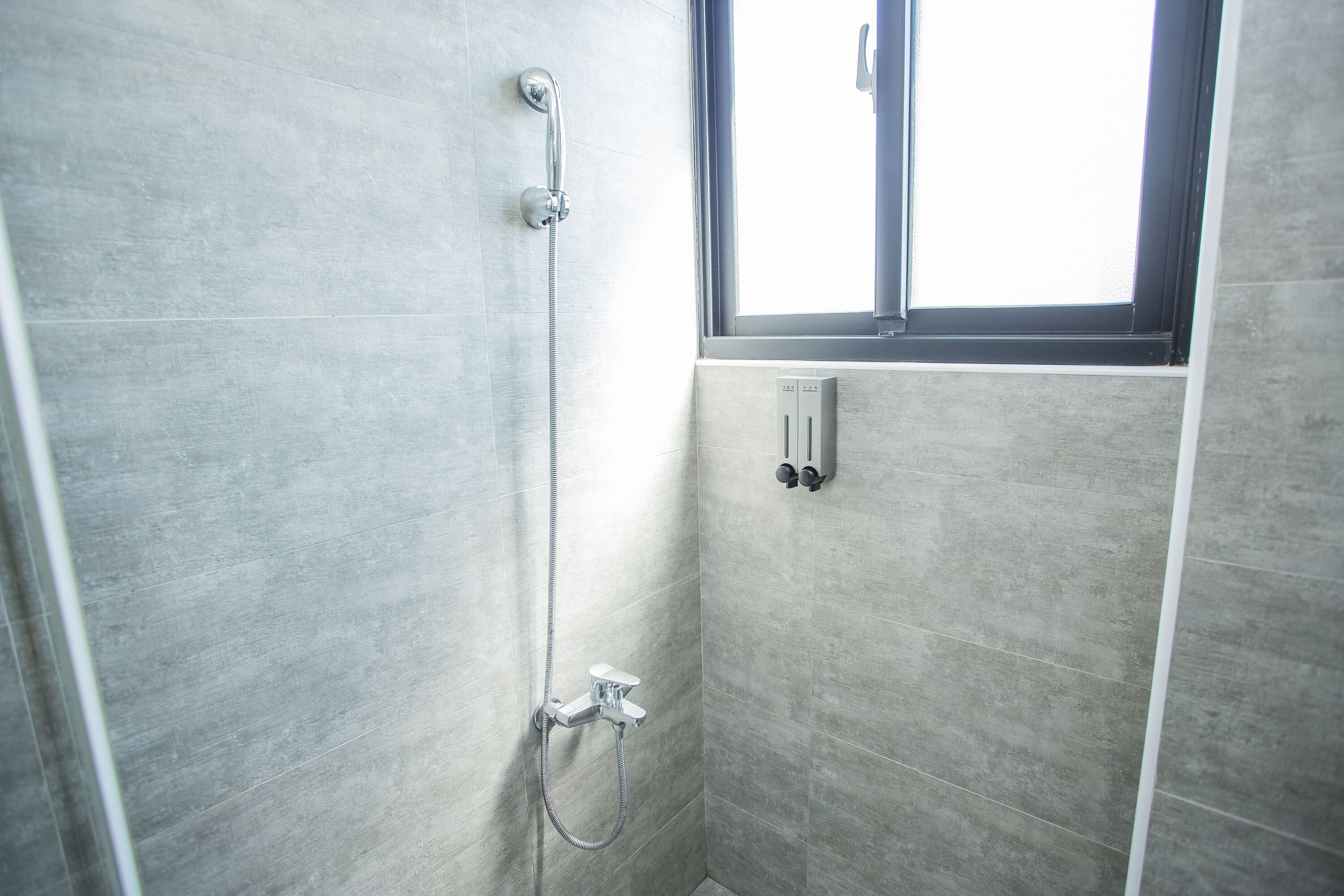 A shower with a handheld showerhead and a wall-mounted control panel.