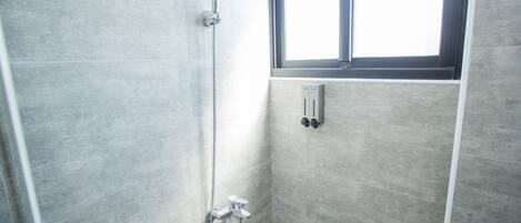 A shower with a handheld showerhead and a wall-mounted control panel.
