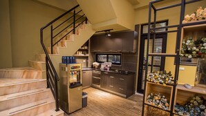 A modern kitchen with dark cabinets, a stainless steel refrigerator, and a wooden staircase. - SunLight Forest (Taitung)