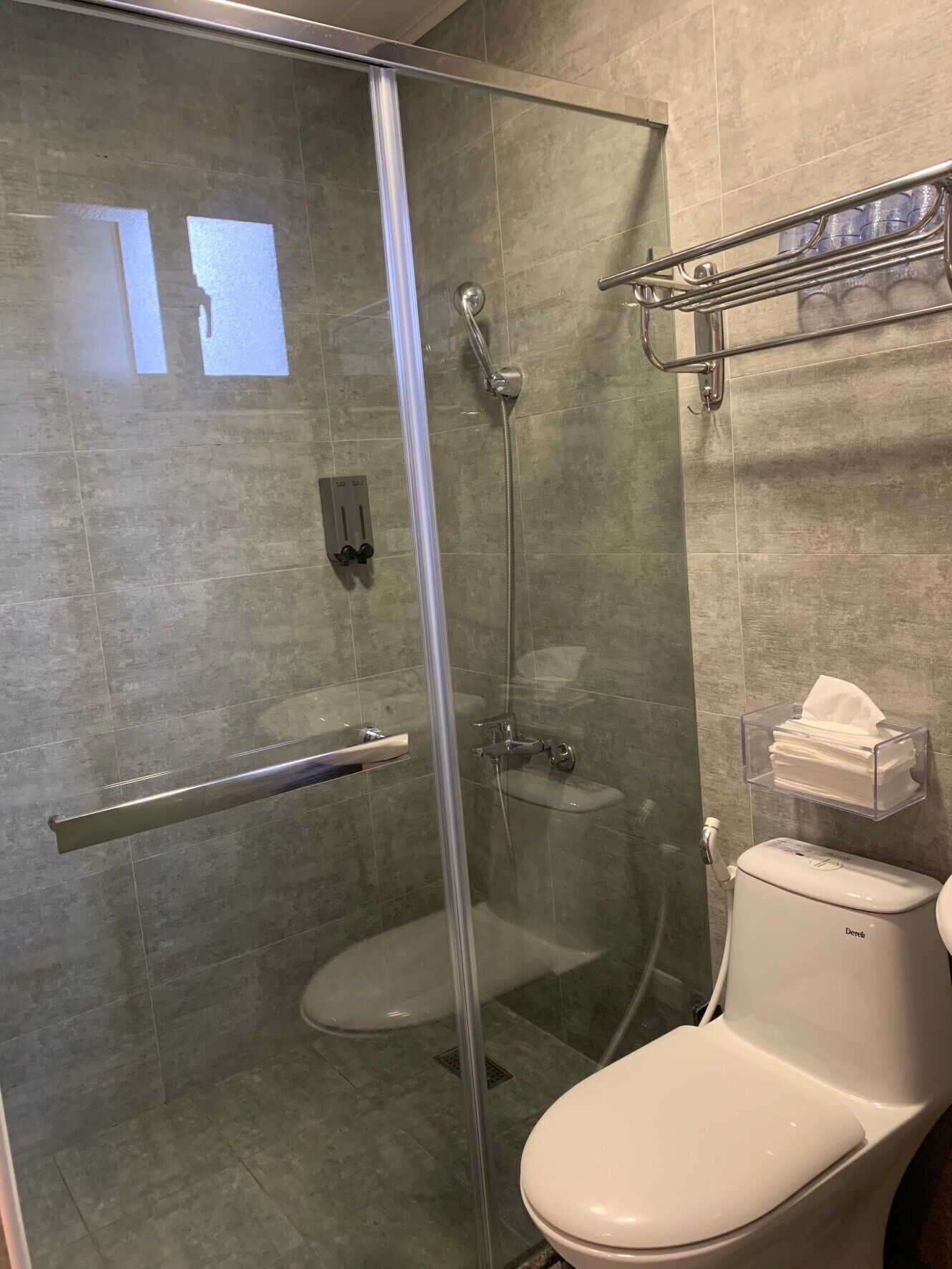 Un baño moderno con ducha de vidrio, inodoro y barra para toallas.