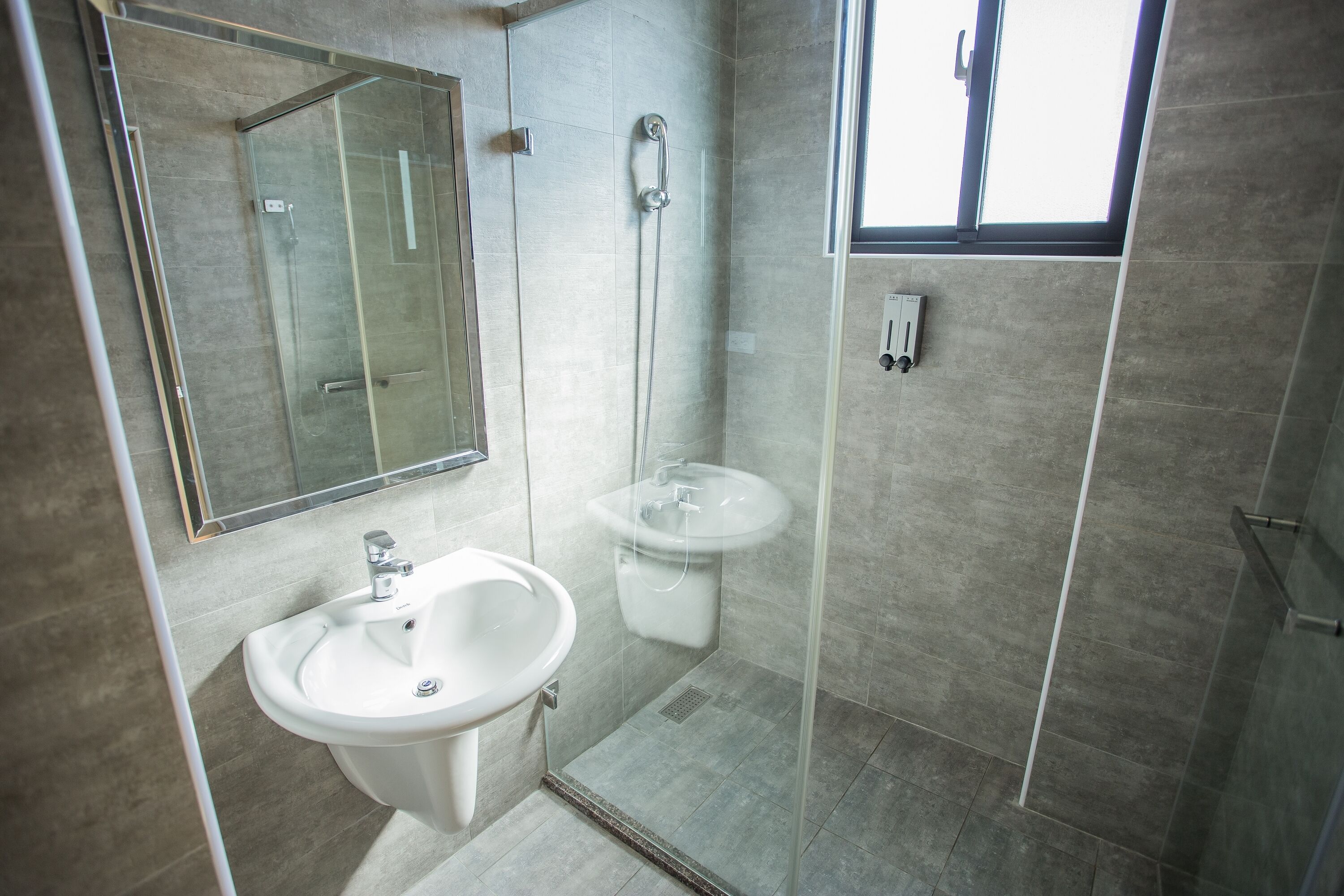 A modern bathroom with a glass-enclosed shower, a sink, and a mirror.