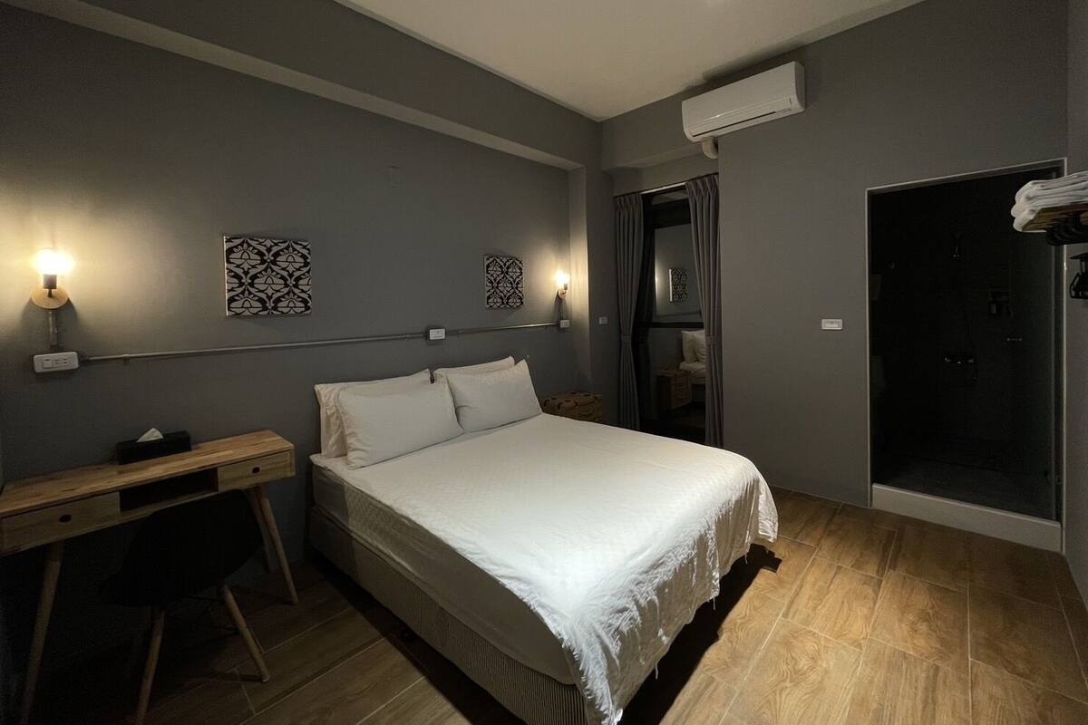 A modern bedroom with a bed, bedside table, and desk.