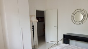Un dormitorio con cama, armario, espejo y lámpara.