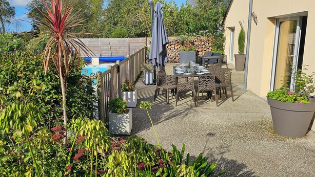 Un patio con piscina, mobiliario exterior y plantas en macetas.