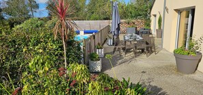 Un espace extérieur aménagé avec une piscine, du mobilier de jardin et des plantes en pot.