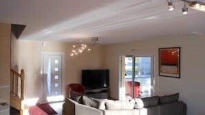 Una sala de estar moderna con un sofá modular, un televisor de pantalla plana y una escalera que sube a otro nivel.