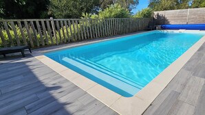 Una piscina rectangular con un muelle de madera y una cerca de madera.