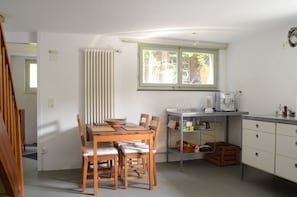 A kitchen with a dining table, chairs, a window, a radiator, and a small cabinet.