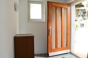Une porte en bois avec un panneau de verre, une petite fenêtre au-dessus, et un meuble en bois sur le côté gauche.
