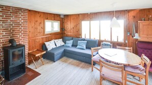 Ein gemütliches Zimmer mit Holzvertäfelung, einer Couch, einem Tisch mit Stühlen und einem Kamin.