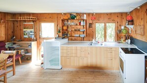 Ein Holzinnenraum mit Küchenzeile, inklusive Kühlschrank, Spüle und Regalen mit Geschirr.