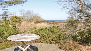 Ein Holztisch mit Metallgestell, umgeben von natürlicher Vegetation und Blick auf das Meer.