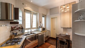 Une cuisine moderne équipée d’une cuisinière à gaz, d’appareils électroménagers en acier inoxydable, d’un lave-vaisselle et d’un coin repas avec une table et des chaises.