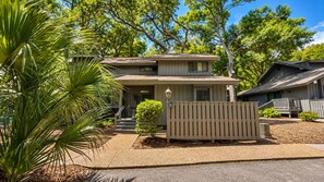 A two-story house with a front porch, a small front yard, and a wooden fence.