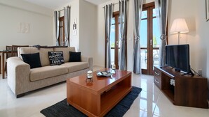 Ein Wohnzimmer mit Sofa, Couchtisch, TV-Schrank und Vorhängen.
