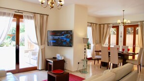Un amplio salón con televisor, sofá, mesa de comedor y sillas.